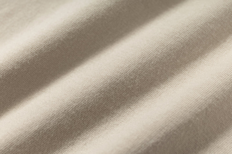 Close-up of beige layered tee fabric with soft folds and visible knit texture
