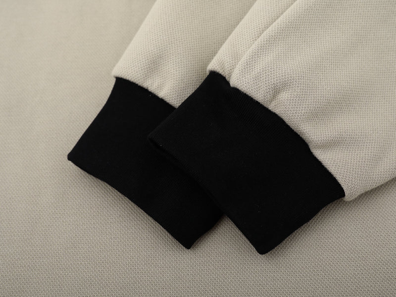 Close-up of black ribbed cuff and beige sleeve on the sweatshirt