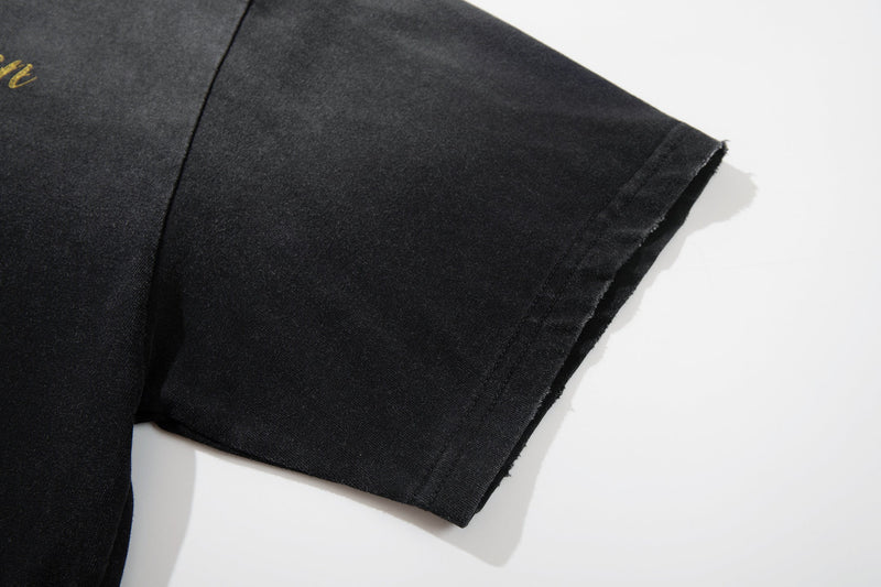 Black washed graphic tee sleeve with raw-cut hem and subtle street art print on soft cotton fabric