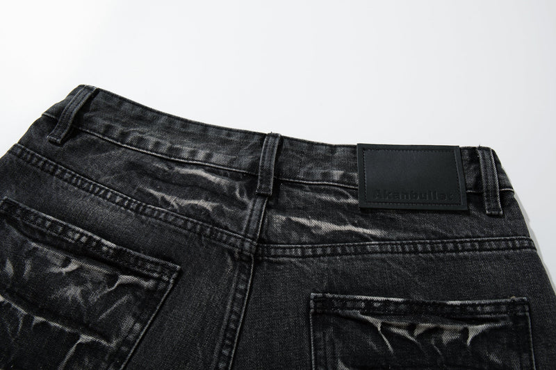 Close-up of the waistband and back leather patch on black cracked-wash jeans