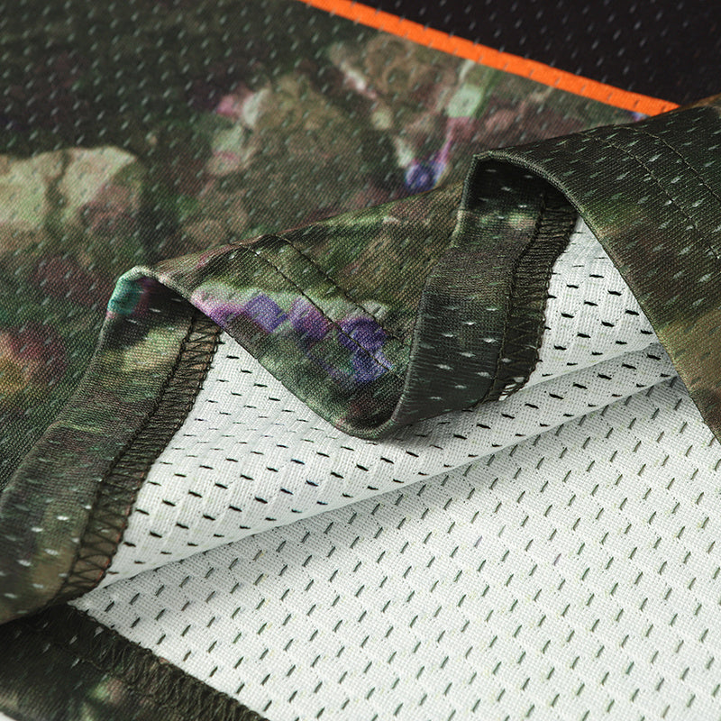 Close-up of camo football jersey fabric with black mesh lining and stitched hem details