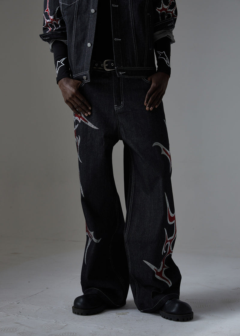 Front view of black denim pants showing the waistband, belt buckle, and flame rhinestone details