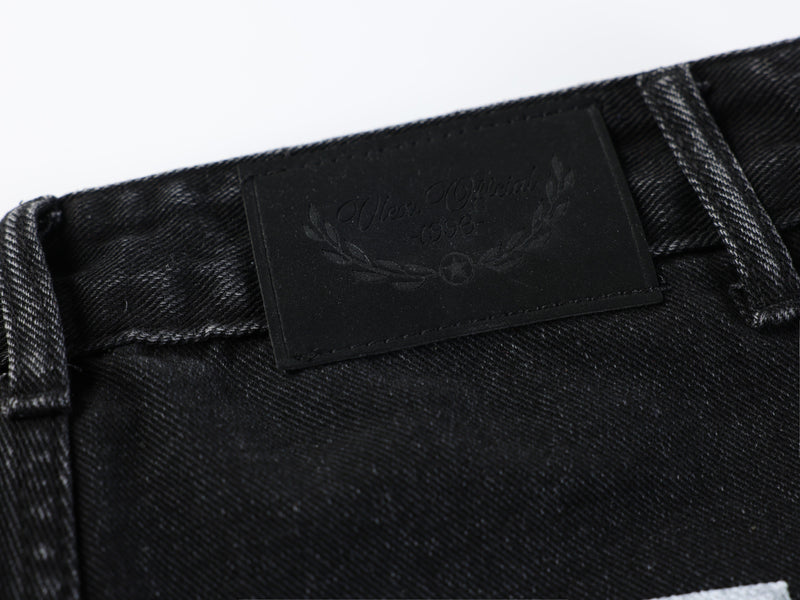 Black leather brand patch with embossed text on the jeans waistband