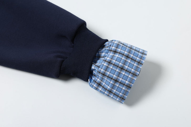 Close-up of navy sleeve cuff with blue plaid fabric and button tab