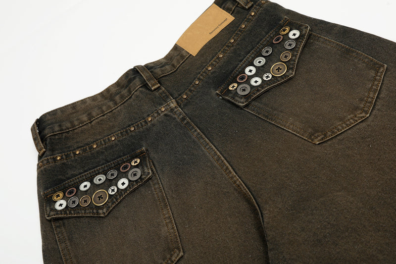 Back pocket close-up on wide-leg jeans with rows of decorative button studs and tan patch