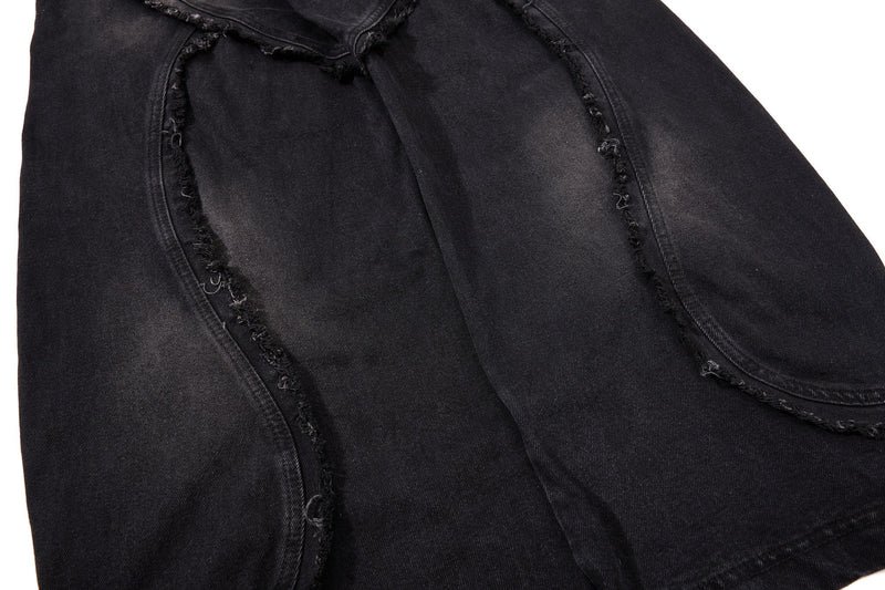 Close-up of black denim leg panel with frayed seam lines and wide-leg shape