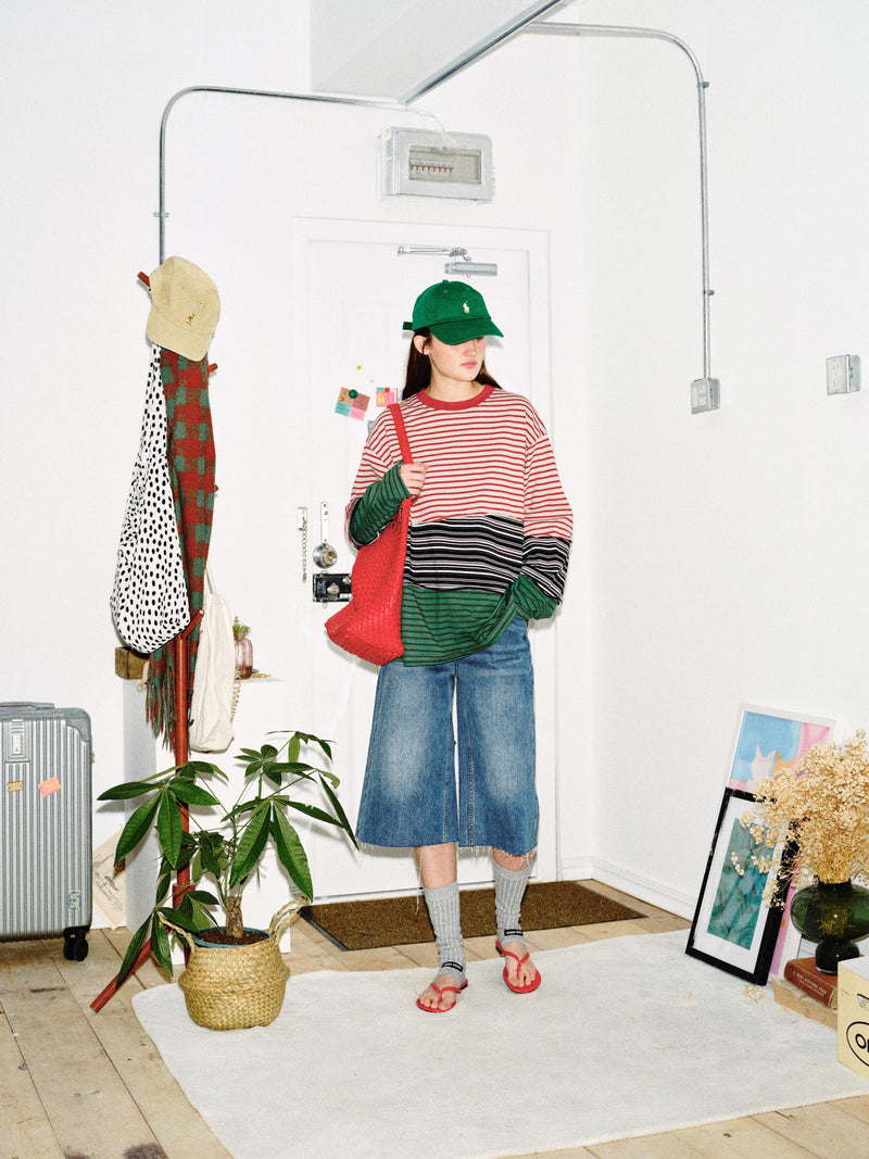 Model holding red bag in color-block striped long sleeve tee, front view