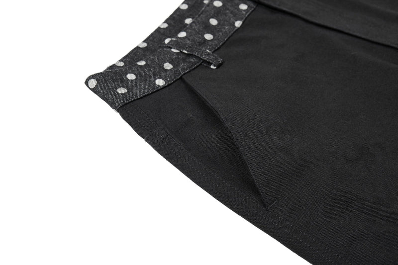 Close-up of black denim leg with solid panel and polka dot trim at the hem