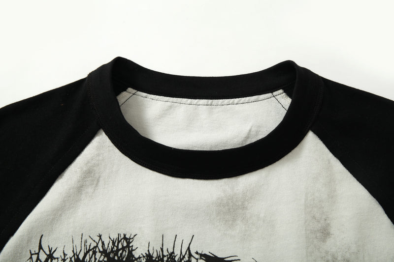 Black and white raglan graphic tee with distressed wash and bold gothic print detail at the neckline and chest