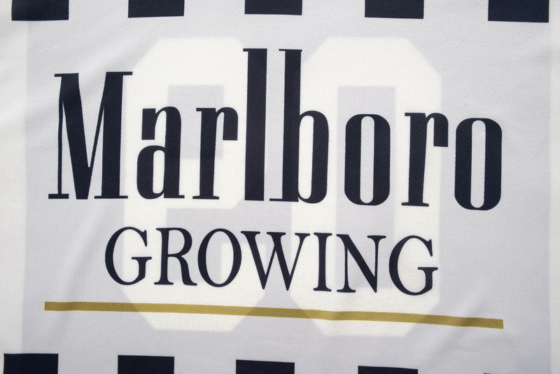 Close-up of a white retro varsity jersey with bold Marlboro Growing graphic, black lettering, and gold stripe detail