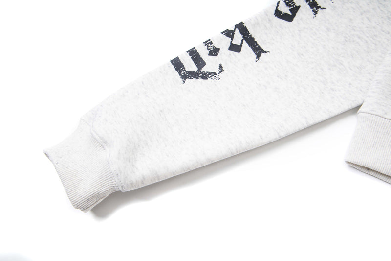 Close-up of white hoodie sleeve with distressed black gothic lettering and ribbed cuff
