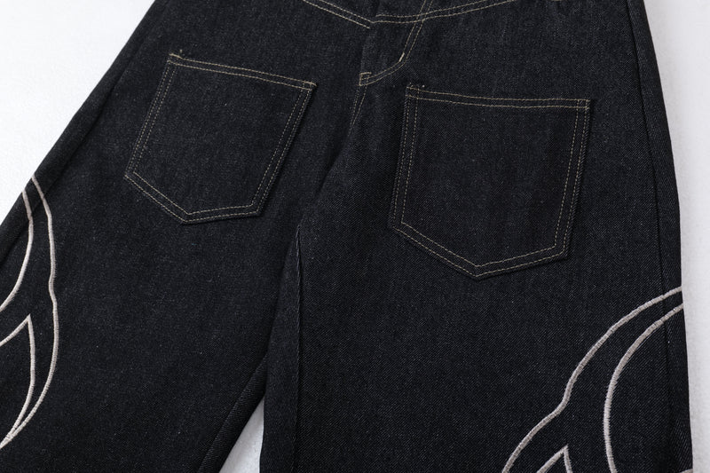Back waist and pockets of dark denim jeans with tribal embroidery on the legs