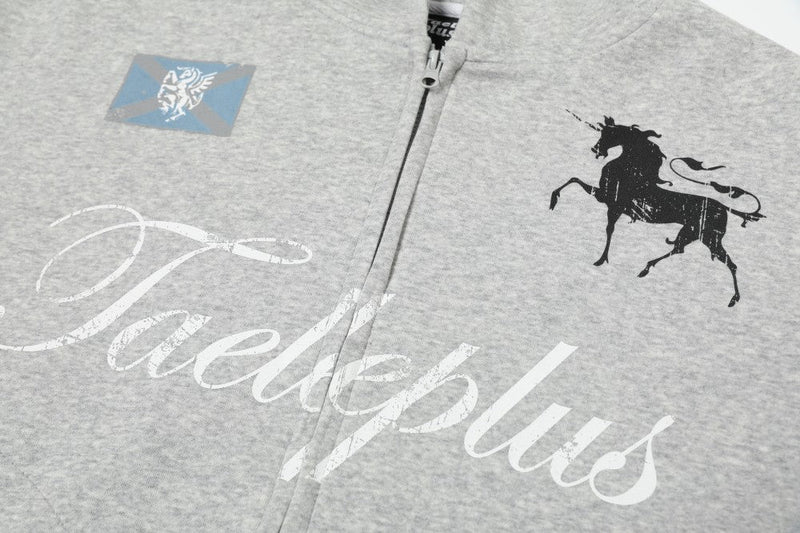 Close-up of front chest on gray zip-up hoodie showing horse graphic, logo patch, and Taeleplus script