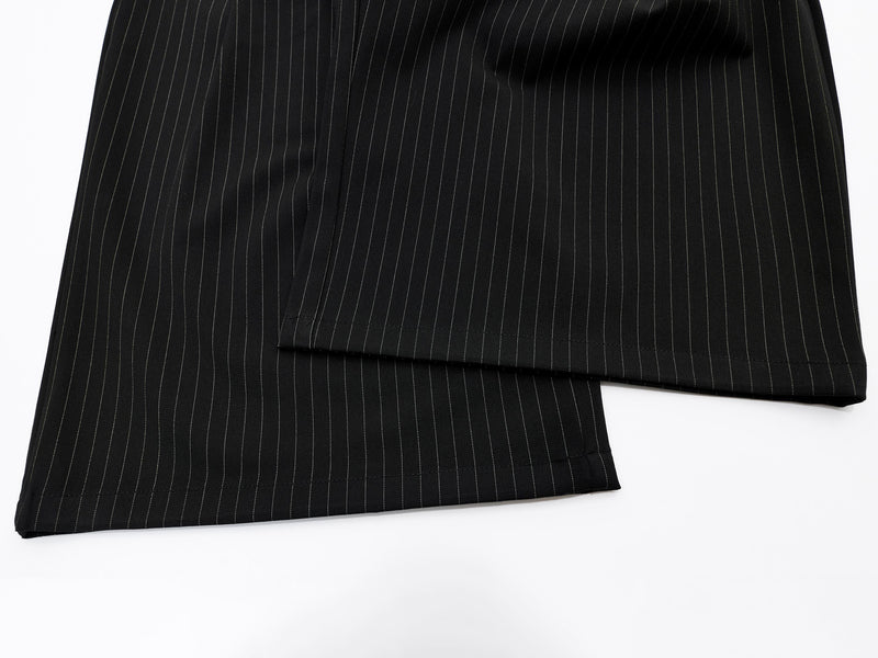 Close-up of lower legs on black pinstripe wide-leg shorts with straight hem