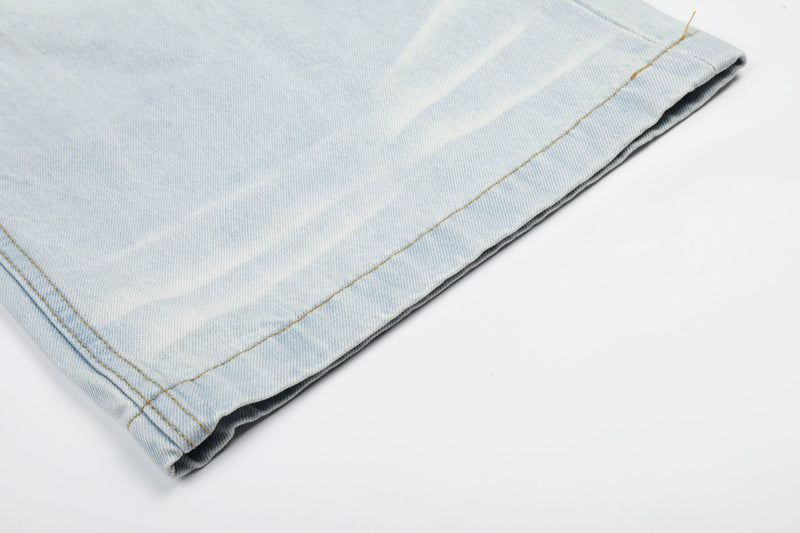 Cuffed hem close-up on light wash denim jeans with yellow stitching