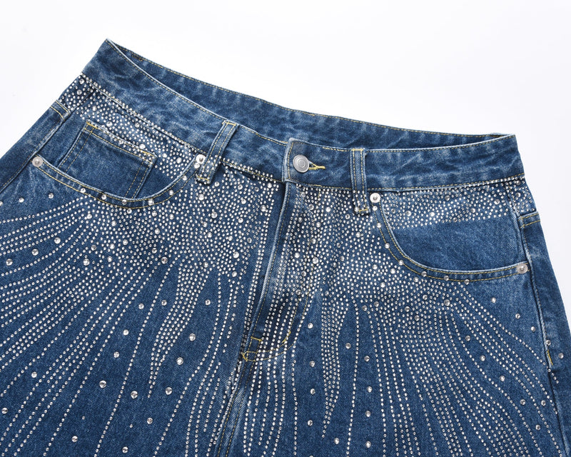 Close-up of blue denim waistband and front pockets with rhinestone burst detailing