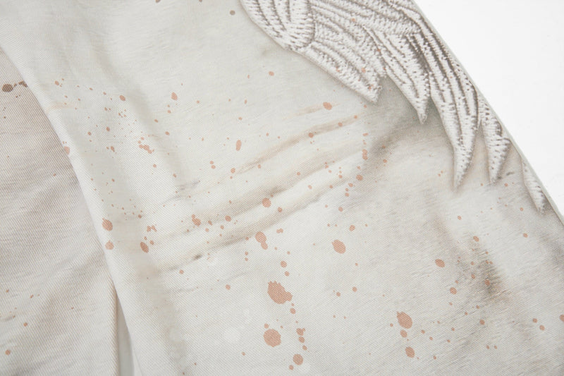 Close-up of cream jeans with splatter print and wing graphic near the back seam