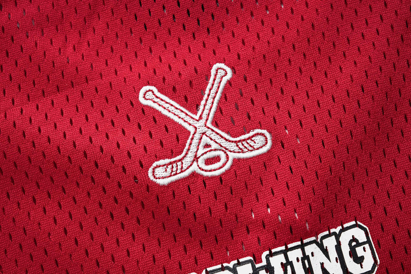 Red mesh hockey jersey fabric with white crossed-sticks embroidery and streetwear lettering details