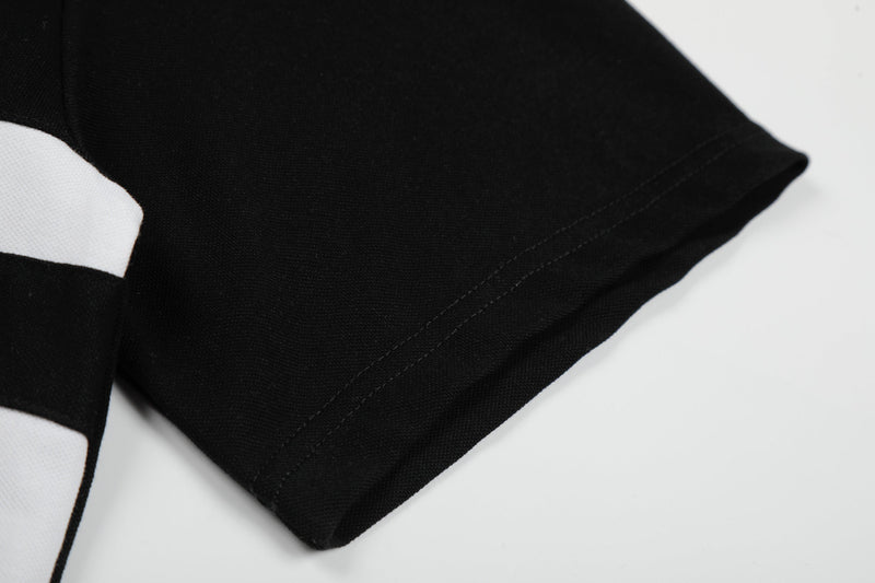 Close-up of a black striped polo shirt sleeve with white cuff and visible stitching detail