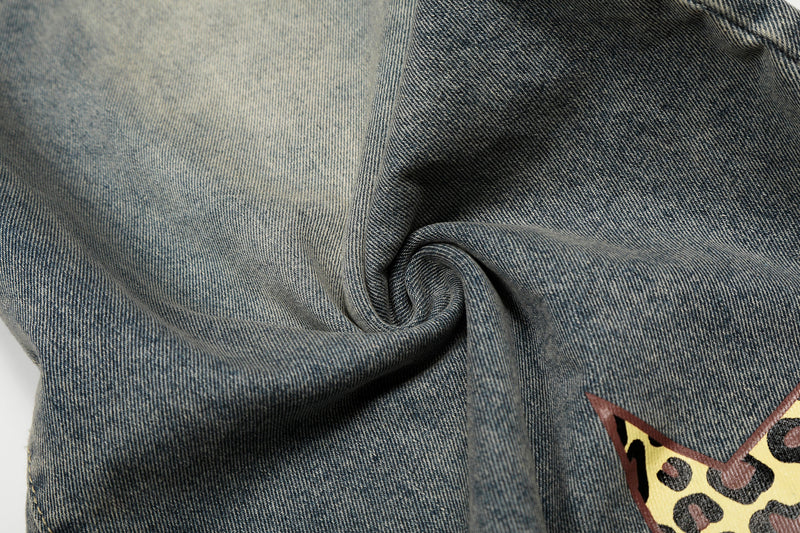 Close-up of wrinkled blue denim fabric with part of a leopard star graphic