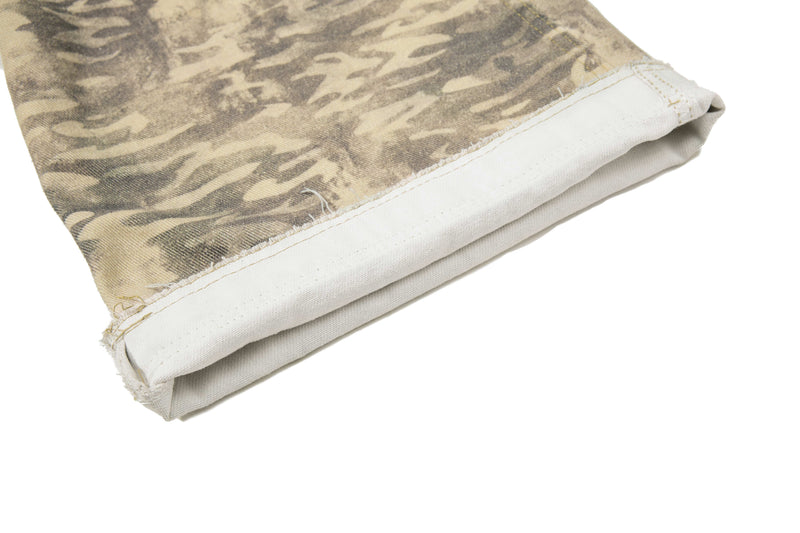 Folded beige camouflage pant cuff with frayed edge and white inner lining