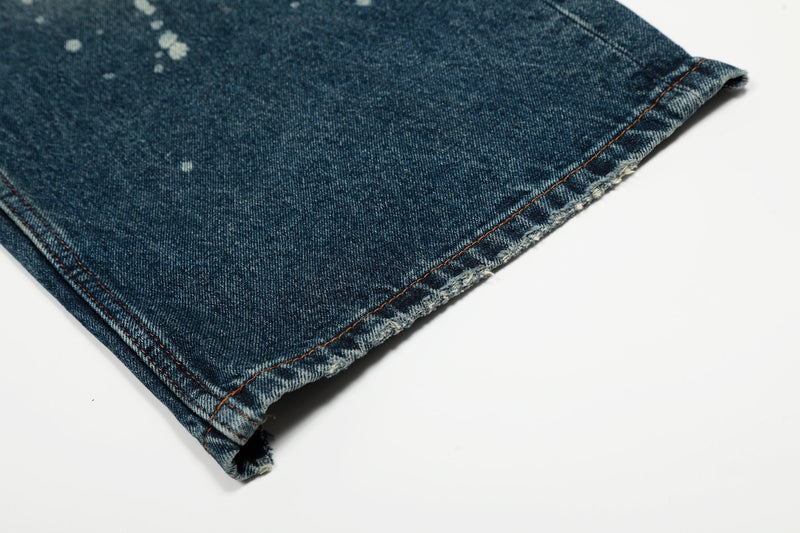 Frayed hem close-up on blue wide-leg jeans with contrast topstitching