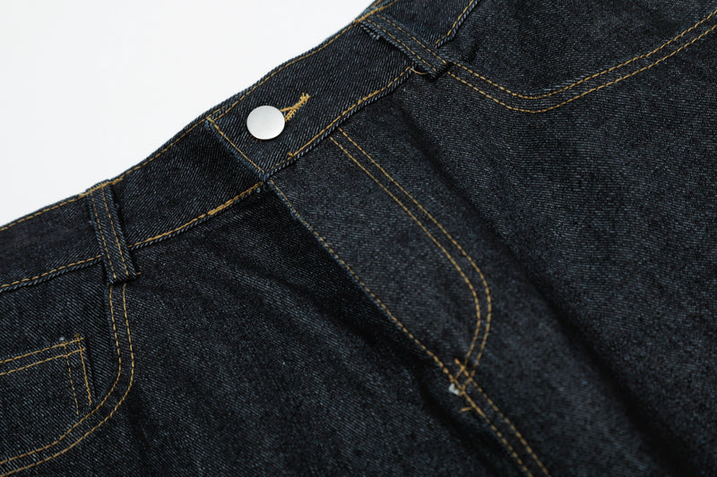 Close-up of black denim waistband with snap button and gold topstitching