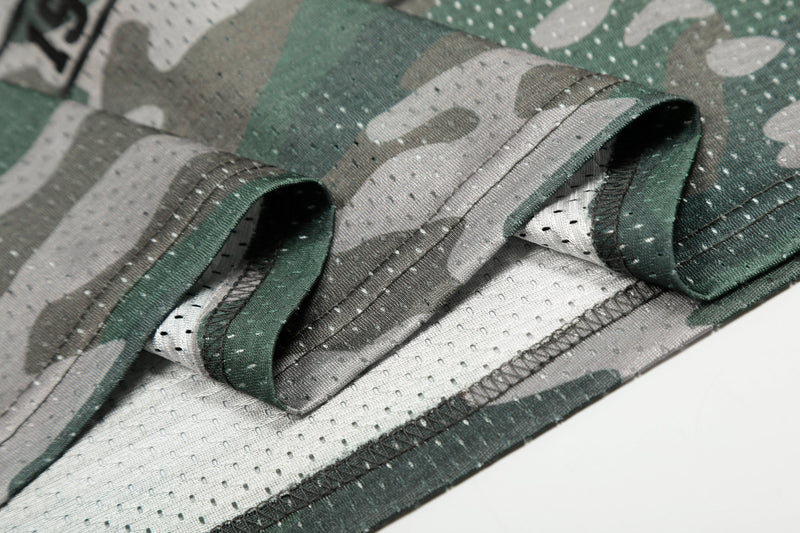 Close-up of a green and gray camo mesh jersey tee with folded hem and breathable athletic fabric texture