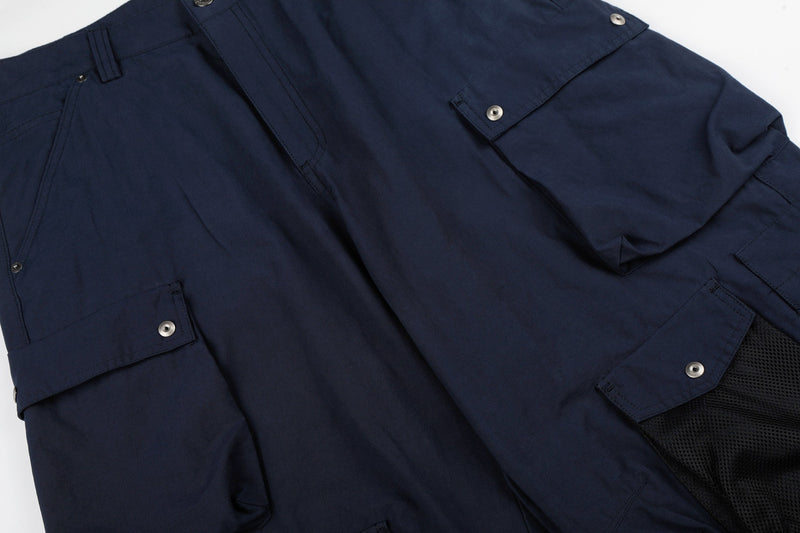 Close-up of navy cargo pants front with flap pockets and mesh lower pocket panel