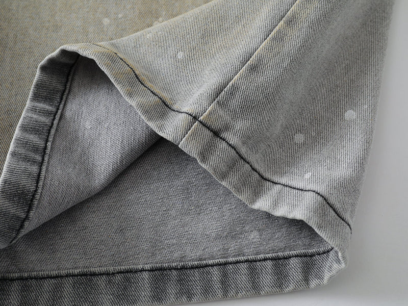 Close-up of hem and inner seam on grey wash denim shorts with faded speckled fabric
