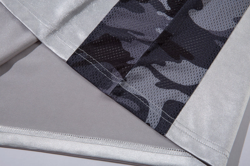 Close-up of camo mesh side panel and hem detail on light gray jersey top