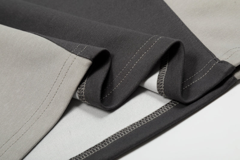Close-up of a black, white, and gray color block cotton tee with visible contrast stitching and folded fabric texture
