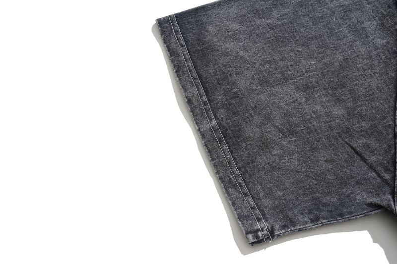 Close-up of a vintage washed black graphic tee sleeve with visible seam stitching and faded distressed texture