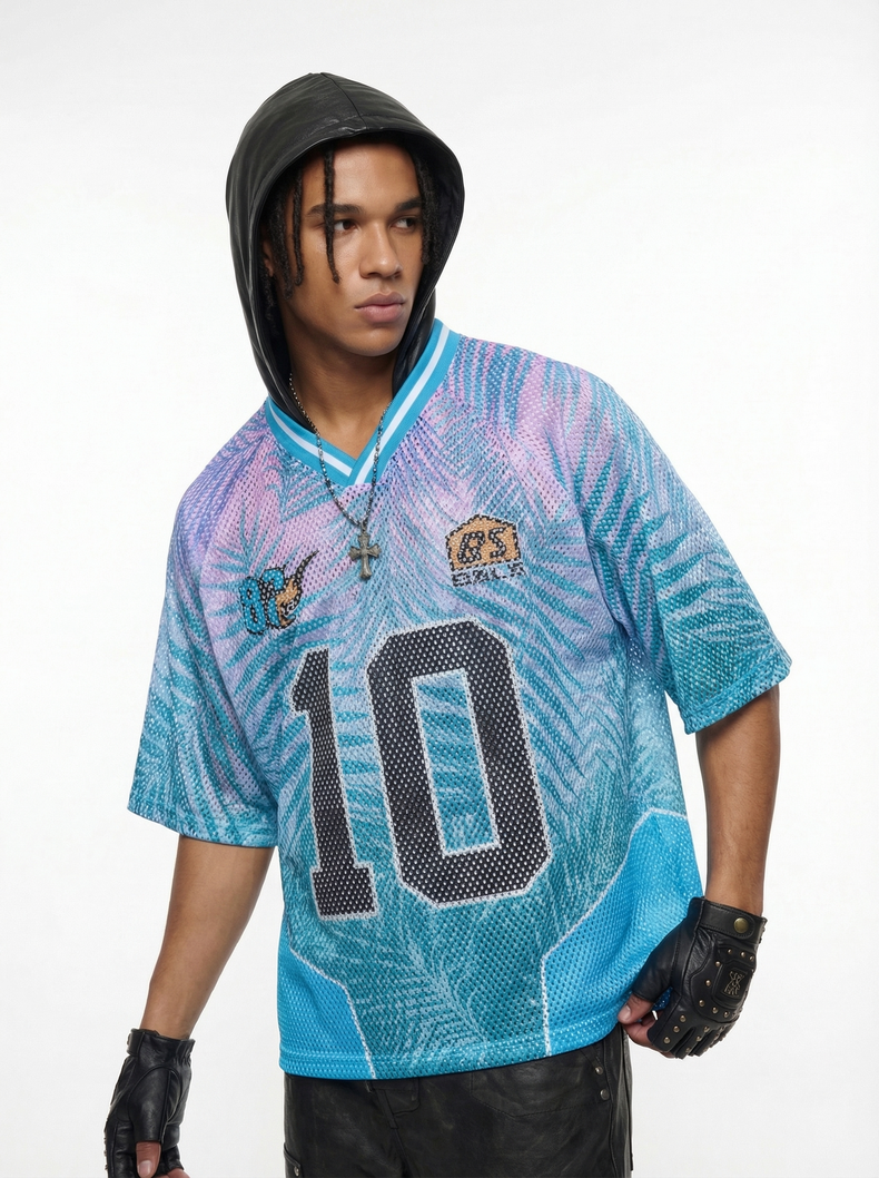 Blue and pink mesh jersey T-shirt with large number 10, palm print pattern, and V-neck trim on a model with black hood