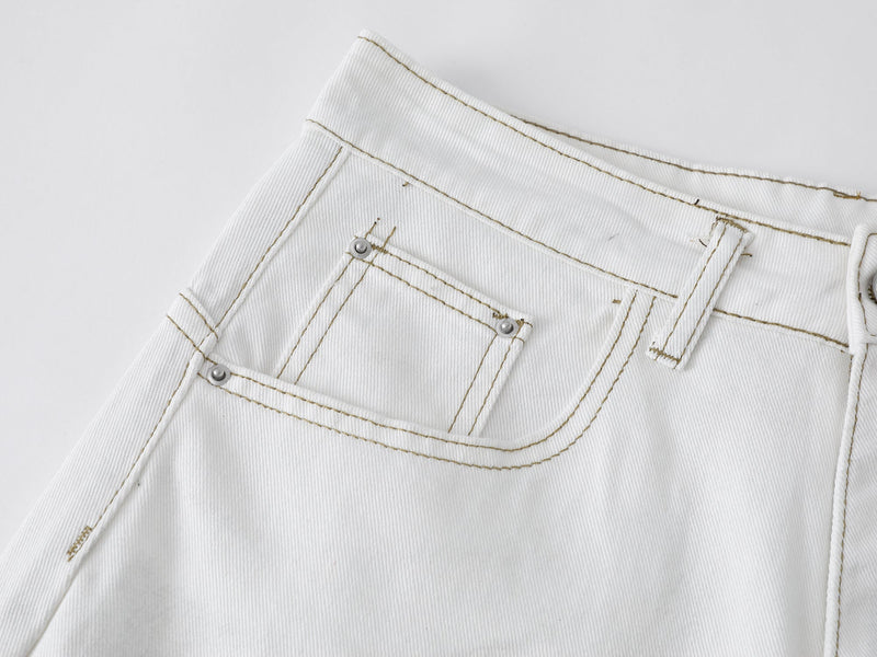 Close-up of the back pocket and waistband on white denim shorts with contrast stitching