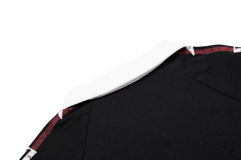 Close-up of a black men's polo shirt with red and white music graphic trim and a folded collar on a white background