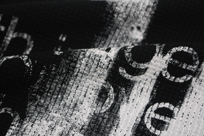Close-up of black oversized tee with distressed white gothic skull and cross graphic print