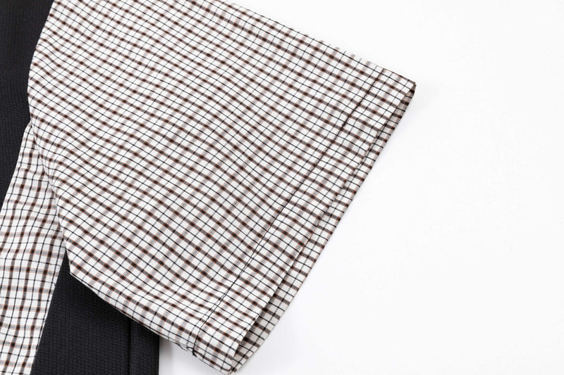 Close-up of an oversized polo shirt sleeve with brown and black plaid panel detail on white fabric