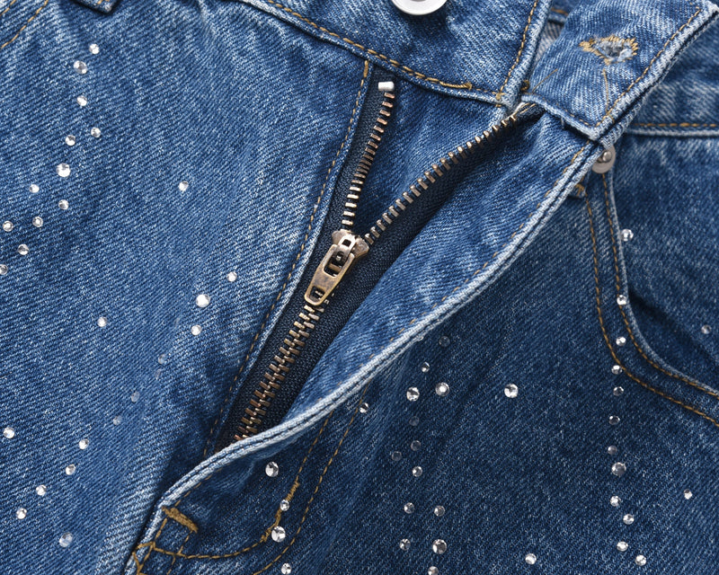 Close-up of blue denim shorts zipper fly and rhinestone detailing