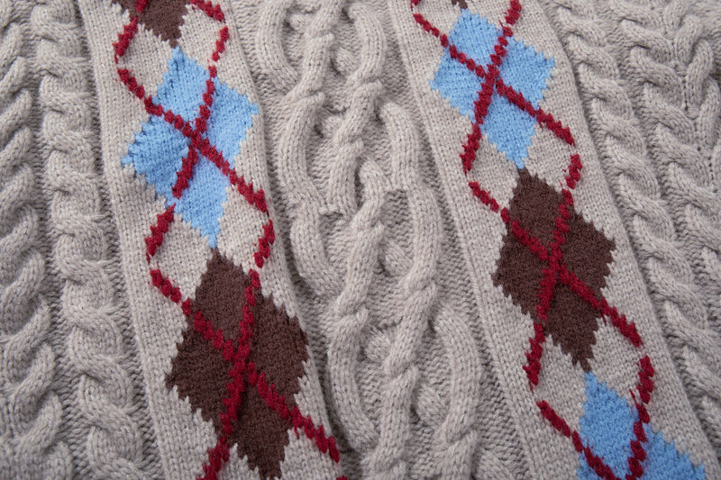 Close-up of argyle diamond panels on beige cable knit sweater in red, blue, and brown