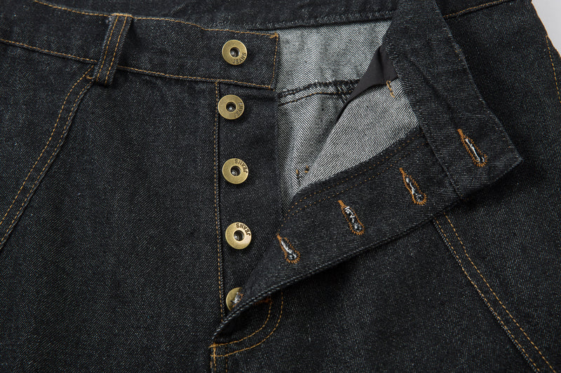 Open fly detail showing inner waistband and button placket on dark denim pants