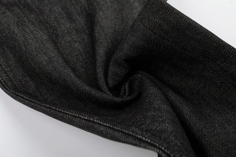 Close-up of black denim fabric folds showing raw textured weave