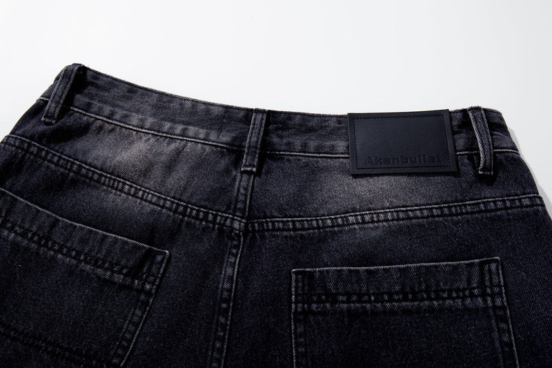 Waistband close-up of dark wash jeans with belt loops and branded patch