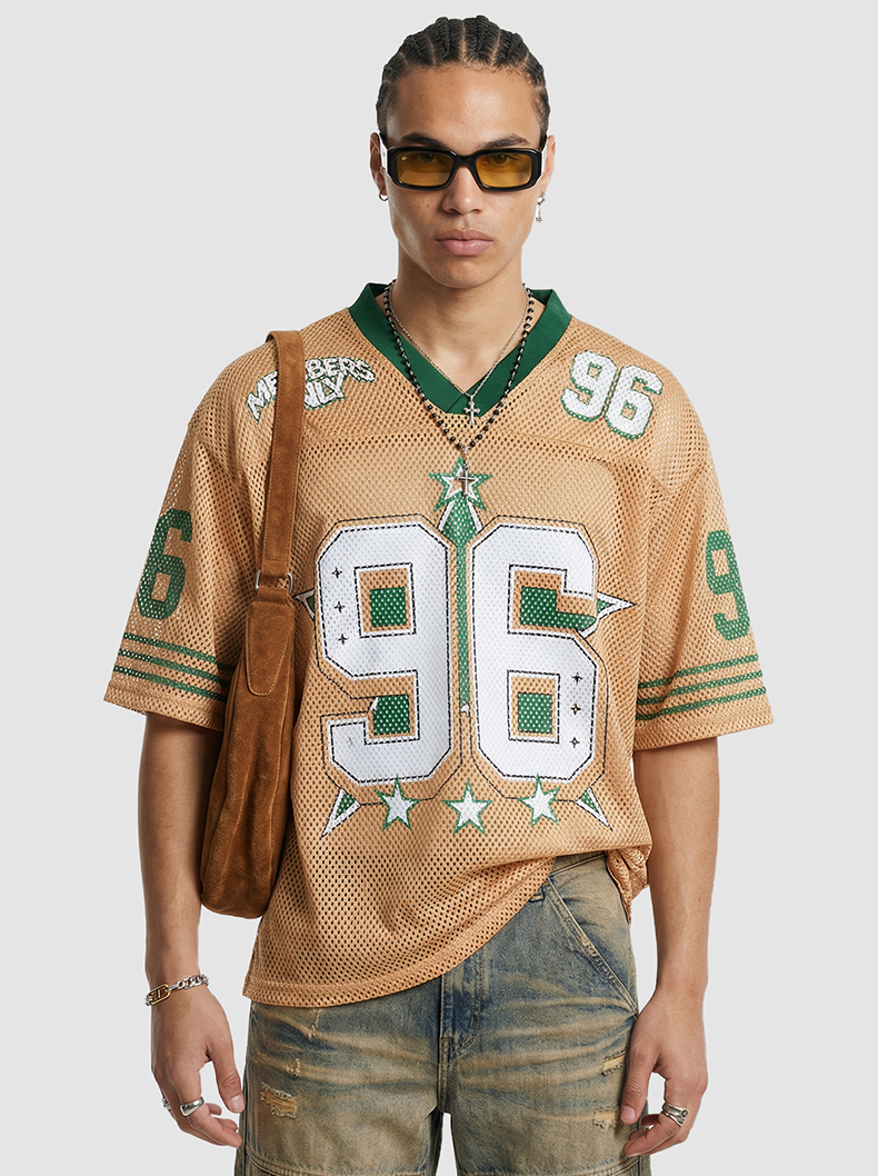 Tan mesh jersey T-shirt with green trim and large 96 graphic, styled on a model with a brown shoulder bag and sunglasses