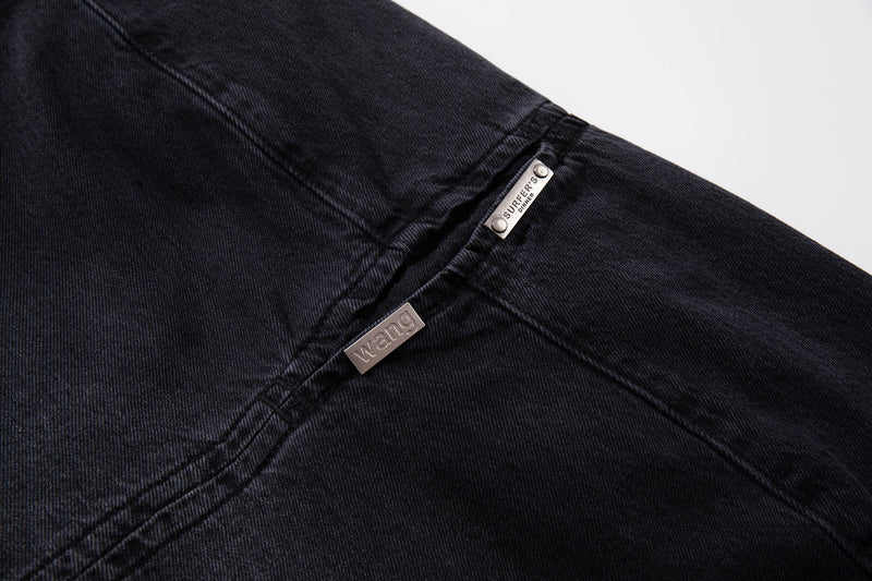 Close-up of split seam on dark wash jeans showing silver-tone metal tab details