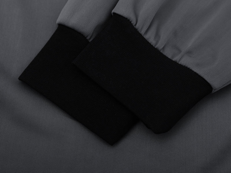 Close-up of black ribbed sleeve cuff on the gray long sleeve football top