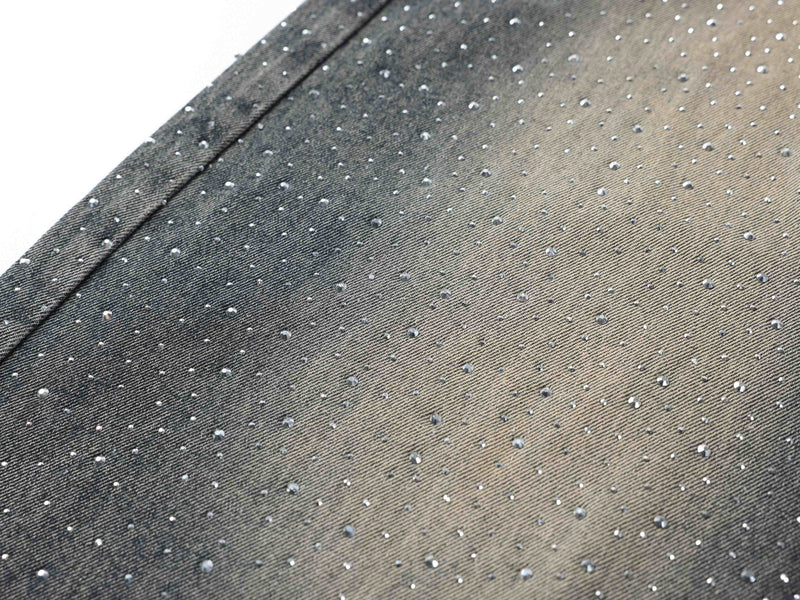 Close-up of rhinestones scattered across faded black denim fabric