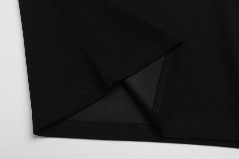 Close-up of a black graphic polo shirt hem with visible stitching and folded fabric detail