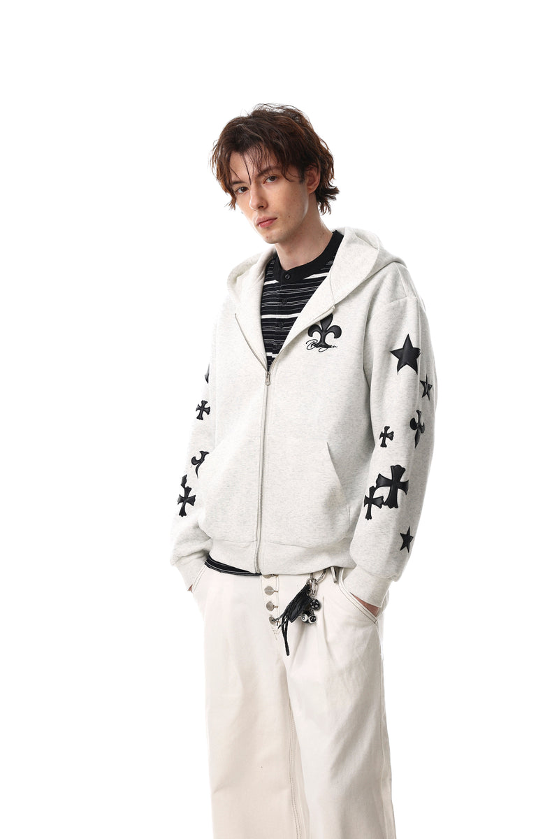 Model wearing light gray zip-up hoodie with black cross graphics and matching streetwear pants