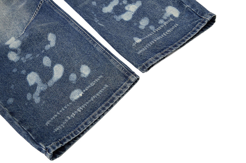 Lower leg close-up with faded spots and stitched hem on blue denim